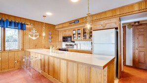 Een keuken met houten kastjes, een centraal eiland, een koelkast en een bordje met de tekst 'Welcome Aboard'.