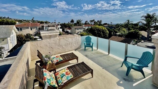 A rooftop terrace with two wooden lounge chairs, a small table, and a blue chair. The terrace overlooks a residential area with houses and trees. - Beautiful La Jolla Village Home, Sleeps 9 (La Jolla)