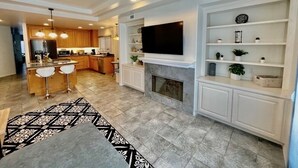 A modern kitchen with a central island, built-in seating, and a flat-screen TV mounted above the fireplace. - Beautiful La Jolla Village Home, Sleeps 9 (La Jolla)