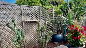 A garden with a stone fountain, various potted plants, and a wooden fence. - Beautiful La Jolla Village Home, Sleeps 9 (La Jolla)