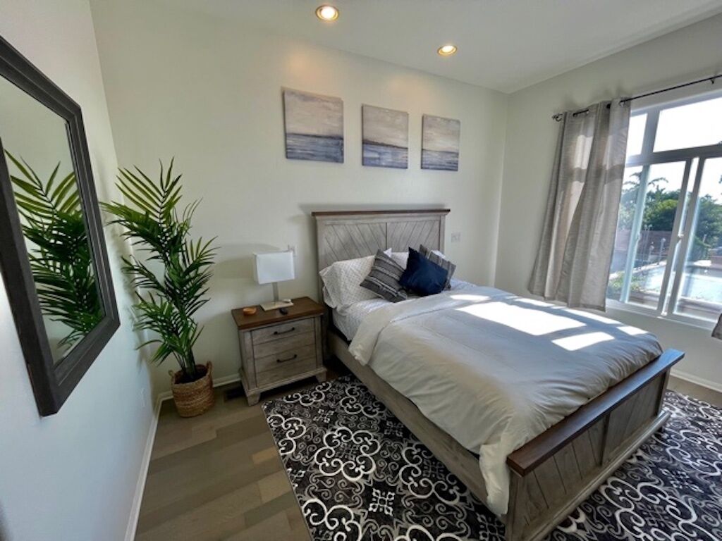 A bedroom with a bed, bedside tables, a mirror, and a window.
