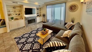 A modern living room with a sectional sofa, a flat-screen TV, a fireplace, and a patterned rug. - Beautiful La Jolla Village Home, Sleeps 9 (La Jolla)