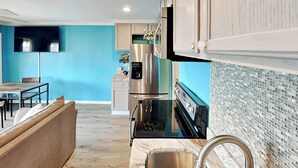 Una cocina moderna con horno empotrado, pileta de acero inoxidable y una zona de comedor con banco de madera.