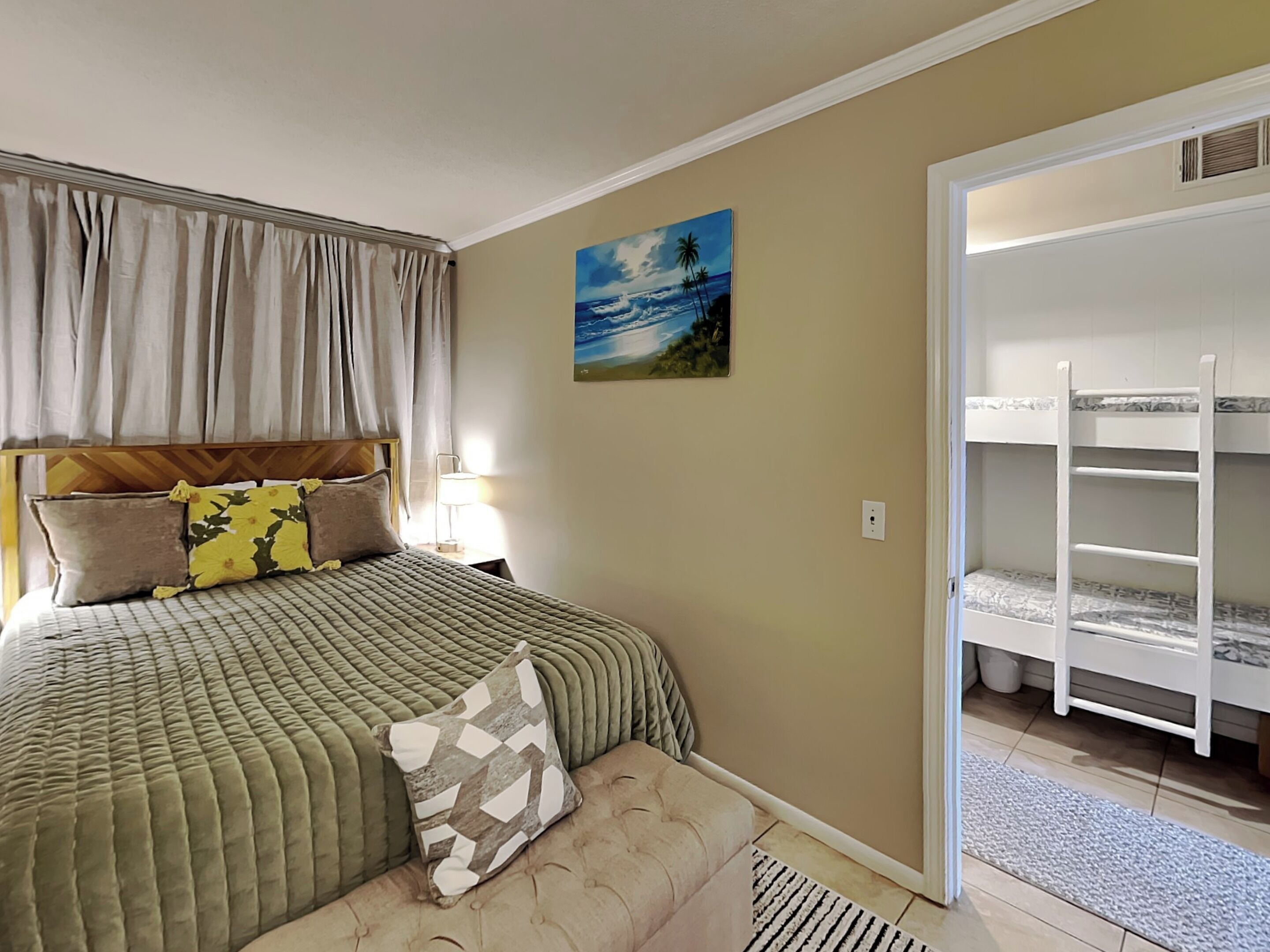 A bedroom with a bed, a nightstand, a painting, and a bunk bed.