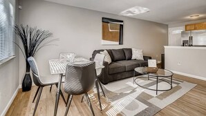 Een moderne woonkamer met een grijze bank, een eettafel met stoelen en een salontafel.