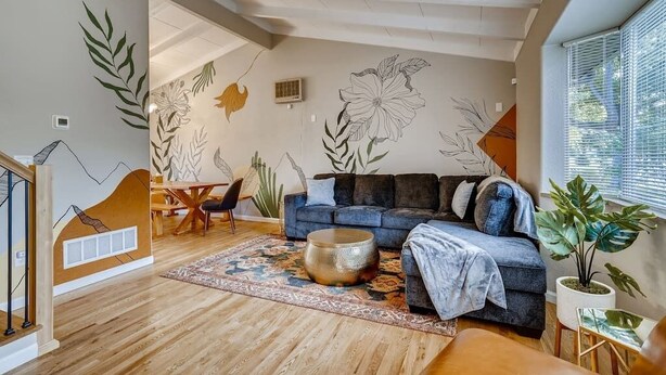 Een moderne woonkamer met een blauwe bank, een bijzettafeltje en een grote plant.
