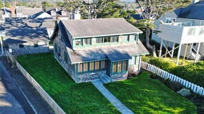 Une maison à deux étages avec un toit végétalisé, un porche à l’avant et un petit jardin devant.