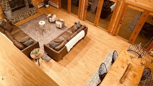 A spacious living area with a stone fireplace, leather sofa, and a large wooden dining table.