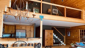 A spacious loft-style interior with a kitchen, dining area, and a staircase leading to an upper level.
