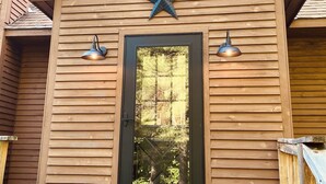 A wooden cabin with a black door, two exterior lights, and a star decoration above the door.