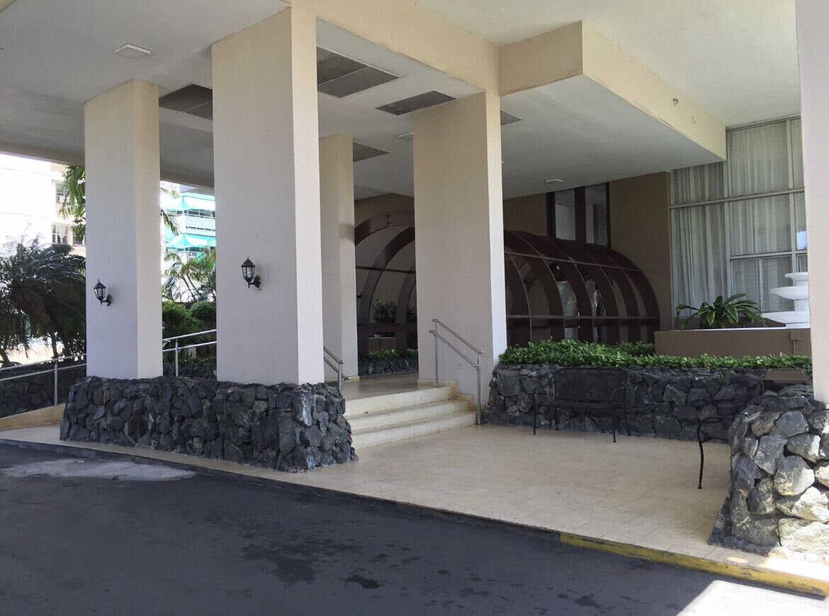 A hotel entrance with a covered walkway, stone pillars, and a staircase leading to the building.