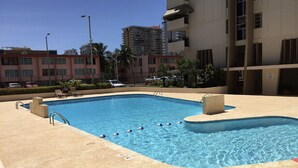 A rectangular swimming pool with a concrete deck, surrounded by a low fence and palm trees. - Penthouse with amazing view beach/city (Carolina)