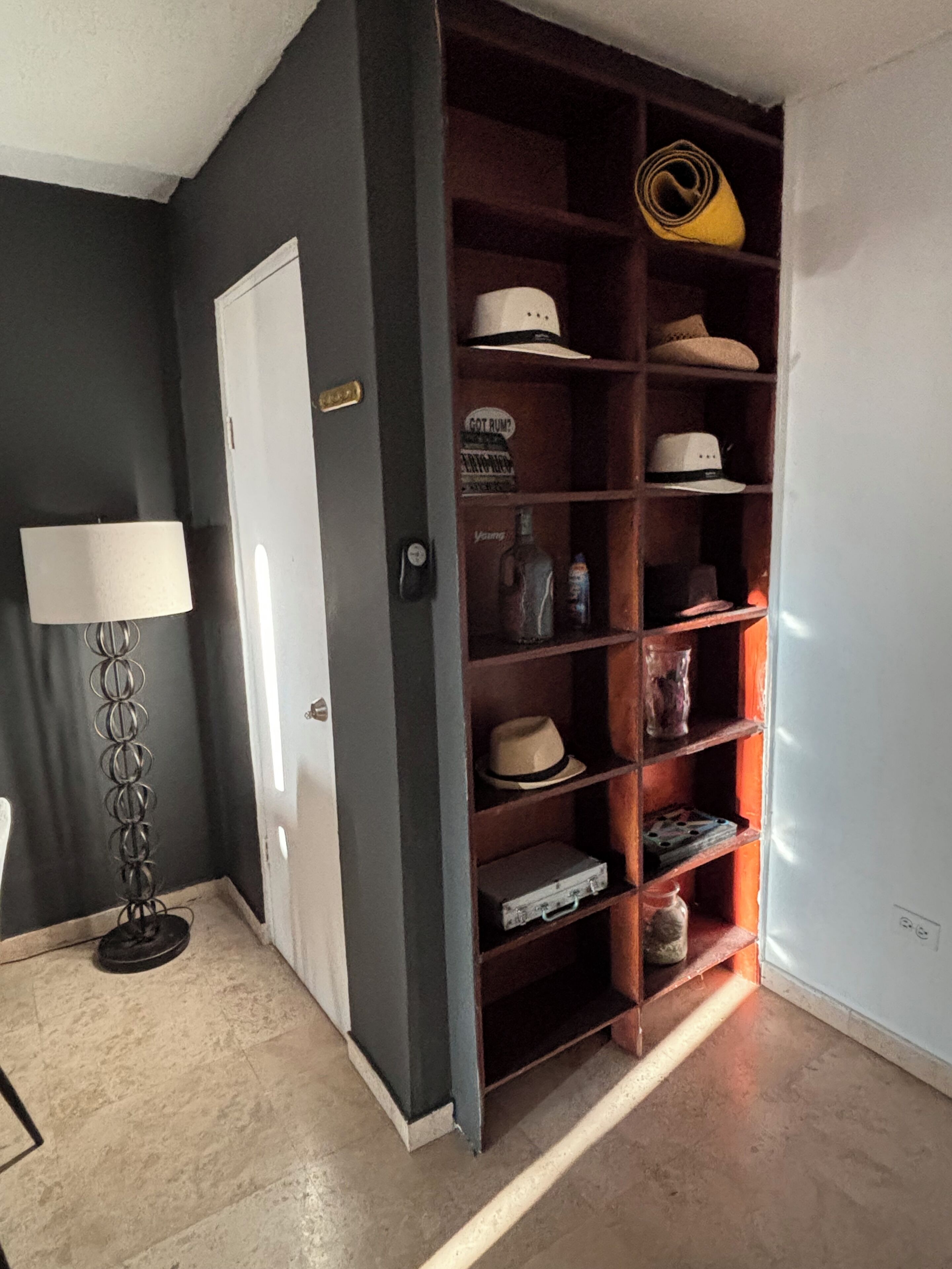 Ein Flur mit Schuhregal, Lampe und Tür.