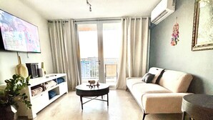 A living room with a sofa, a coffee table, a TV, and a plant. - Penthouse with amazing view beach/city (Carolina)