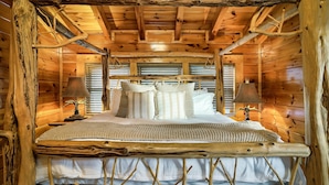 Habitación de cabaña de madera con cama, almohadas y dos lámparas.