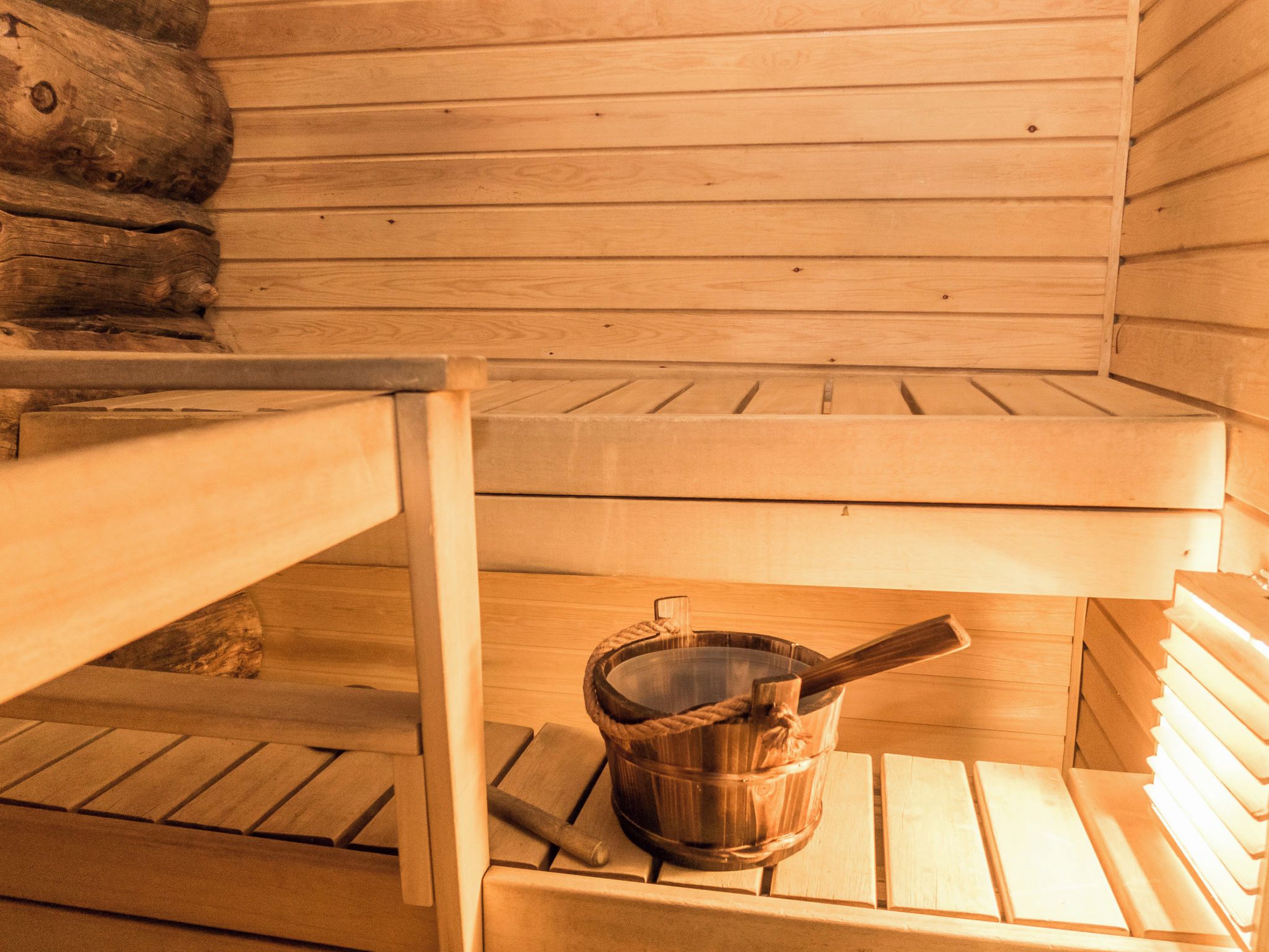 A sauna with wooden benches and a wooden bucket with a paddle.