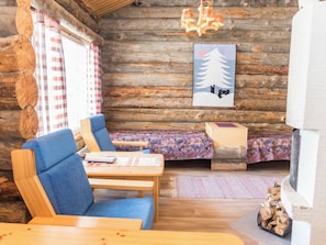 Et interiør af en træhytte med spiseområde, sofa, seng og pejs.