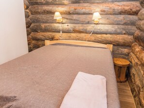 A bed in a log cabin room with two wall-mounted lamps. - Rukankuukkeli c 24 by Interhome (Kuusamo)