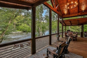 Une terrasse en bois avec des sièges extérieurs donnant sur une rivière.