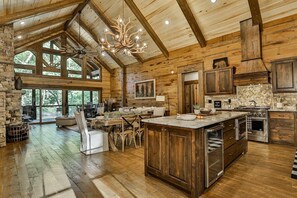 Un intérieur spacieux de chalet en bois, comprenant une grande salle à manger, une cuisine et une cheminée en pierre.