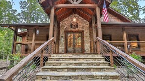 A rustic cabin with a stone entrance, wooden steps, and a metal railing. - Riverscape | Ellijay, GA (Ellijay)