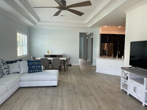 Een moderne woonkamer met een modulaire bank, een eethoek, een keuken en een plafondventilator.