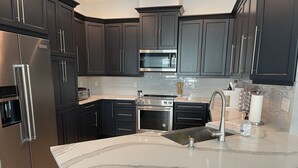 Una cocina moderna con muebles oscuros, electrodomésticos de acero inoxidable y encimera de mármol.