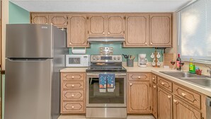 Una cucina con mobili in legno, un frigorifero in acciaio inossidabile, un forno a microonde, un forno e un lavandino.