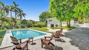 Une piscine avec des chaises longues et une maison moderne en arrière-plan.