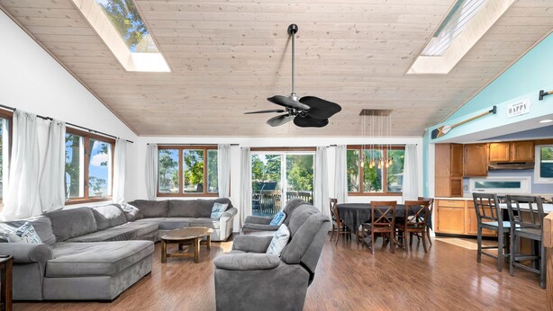 A spacious living area with a sectional sofa, a recliner, a dining table with chairs, and a kitchen area with wooden cabinets.