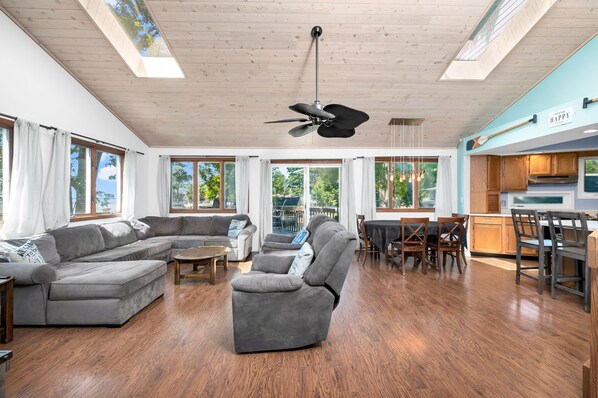 A spacious living area with a sectional sofa, a recliner, a dining table with chairs, and a kitchen area with wooden cabinets.