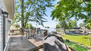 A deck with outdoor furniture, a grill, and a view of a lake and dock area.