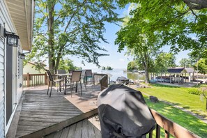 A deck with outdoor furniture, a grill, and a view of a lake and dock area.