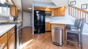 A modern kitchen with wooden cabinets, stainless steel appliances, and a built-in island with seating.