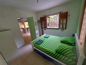 A bedroom with a bed, a window with shutters, a radiator, and a door leading to a balcony.