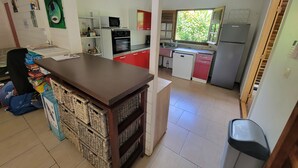 Una cuina compacta amb microones, forn i rentatge. Hi ha una zona de dinar amb taula i cadires.