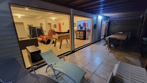 Zona de pati coberta amb taula de futbolí, seients relaxants i taula de menjador.