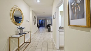 A hallway with a mirror, framed artwork, and a console table with a vase. - 9 BR/5 BA Resort Villa in Storey Lake Closed to Disney  (Kissimmee)