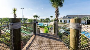 A rope bridge leading to a pool area with a view of a building and palm trees. - 9 BR/5 BA Resort Villa in Storey Lake Closed to Disney  (Kissimmee)