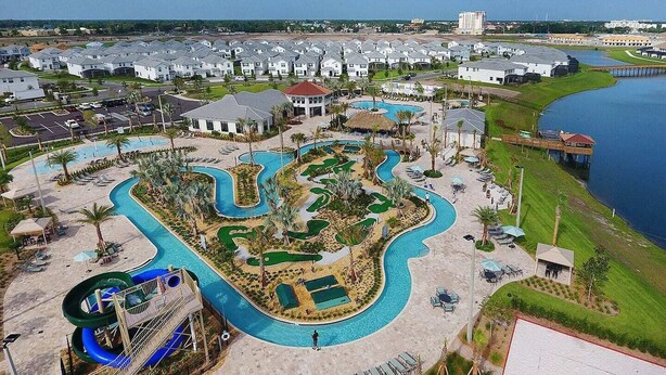 An aerial view of a resort with multiple swimming pools, a water slide, and a golf course. - 9 BR/5 BA Resort Villa in Storey Lake Closed to Disney  (Kissimmee)