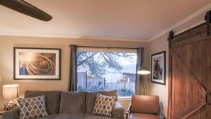 A cozy living room with a sofa, armchair, and a large window with a view of a snowy yard.