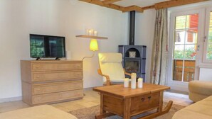 Een gezellige woonkamer met een televisie, een open haard, een houten tafel en twee banken.