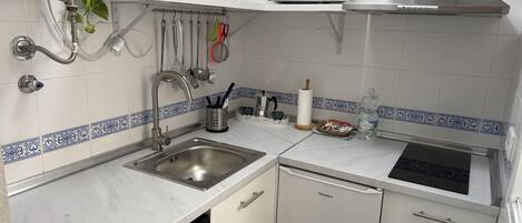 Una cocina moderna con armarios blancos, un lavamanos de acero inoxidable, lavavajillas y microondas.