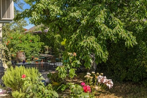 A garden with a stone pathway, potted plants, and a table with chairs. - Cozy Home with private Garden, Dražice, Croatia (Dražice)
