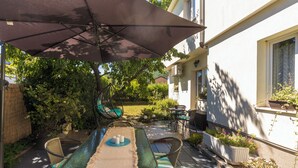 An outdoor patio with a table and chairs, a large umbrella, and potted plants.