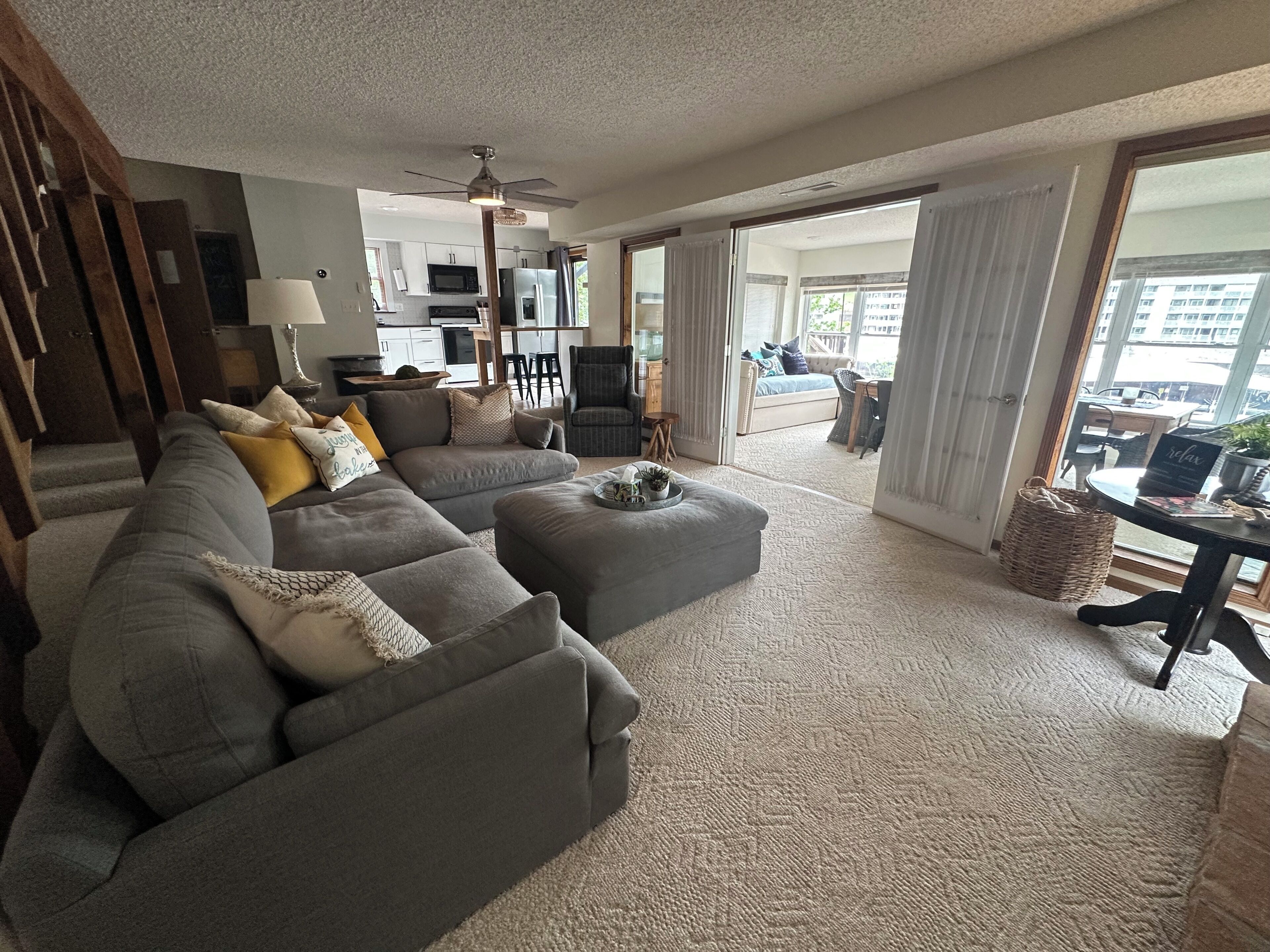 A living room with a sectional sofa, ottoman, and a dining area with a table and chairs.