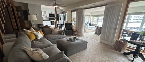 A living room with a sectional sofa, ottoman, and a dining area with a table and chairs.