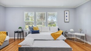 A modern bedroom with a large bed, a bedside table, a small side table, and a window with blinds. - 5BR w/ Gameroom & 1K WiFi - Med Ctr, Downtown, NRG - Sleeps 15 (Houston)