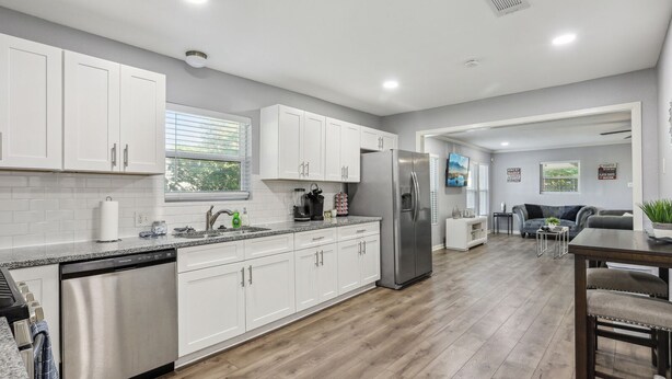 A modern kitchen with white cabinetry, stainless steel appliances, and a wooden floor. - 5BR w/ Gameroom & 1K WiFi - Med Ctr, Downtown, NRG - Sleeps 15 (Houston)