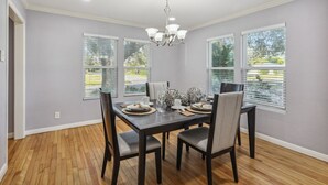 A dining room with a dark wooden table set for four, surrounded by chairs with cushioned seats. - 5BR w/ Gameroom & 1K WiFi - Med Ctr, Downtown, NRG - Sleeps 15 (Houston)
